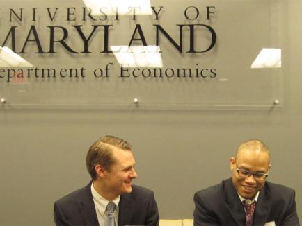 two men sitting in front of UMD sign